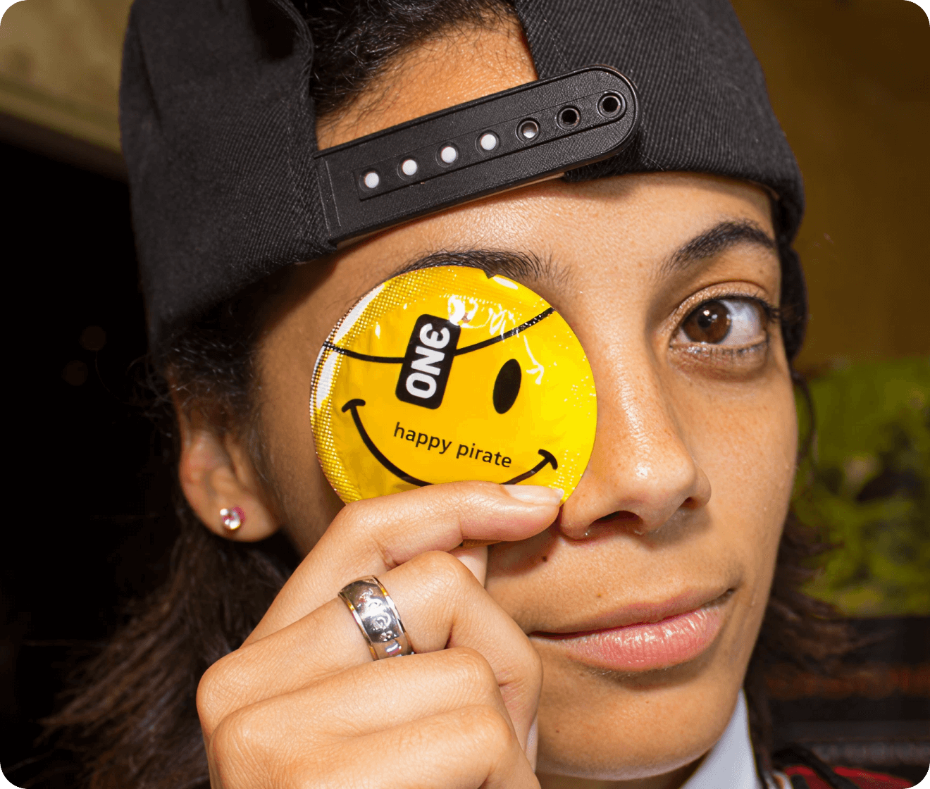 Person holding a yellow 'ONE happy pirate' product in front of their eye.