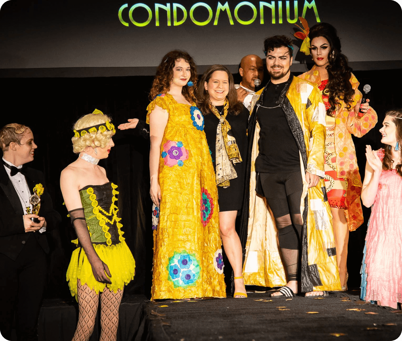 lots of people standing at a stage with the word condomonium in the background